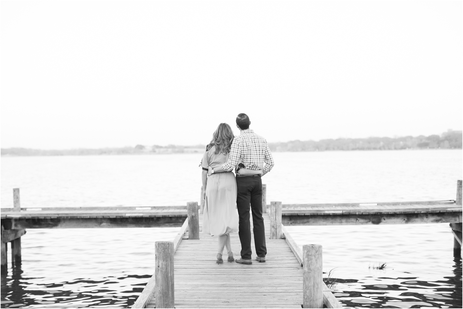 engaged couple looking out onto the water at white rock lake